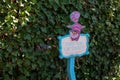 Sign board with "This way or that" writing and The Cheshire Cat against a bush in Disneyland, Paris