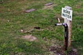 A sign for bore water in the midst of a dried out lawn.