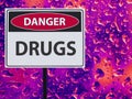 Sign danger drugs and neon drop on the glass.