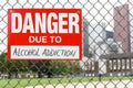 Sign danger due to alcohol addiction hanging on the fence