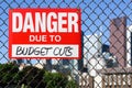 Sign danger due to budget cuts hanging on the fence