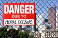Sign danger due to moral decline hanging on the fence