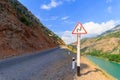 Sign a dangerous curve on a mountain road, near the cliff. Uzbekistan, western Tien-Shan Royalty Free Stock Photo