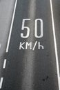 Sign on dark asphalt road 50 km in hour. Speed limit in European towns. Safety measures to reduce number of fatal accident Royalty Free Stock Photo