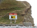 A sign depicting dangerous cliffs on a pebble beach in the UK Royalty Free Stock Photo