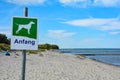 Sign with a dog and the German word Begin on the sandy beach