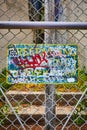 Sign on fence left nearly illegible with graffiti saying Trespassing Loitering Forbidden By Law