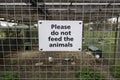 A Sign on the fence of a petting zoo stating do not feed the animals