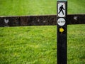 Sign on a fence walking man and direction arrow to the right. and 2 km distance.