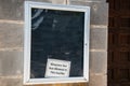Sign with a glass widow door on a stone block wall. There is a sign that says that no weapons are allowed in the facility.