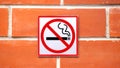 Sign hangs on a brick wall warning that smoking is not permitted in the area