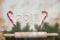 Sign happy New year 2018 in the flour on the wooden table decorated with red candies, christmas three branch powdered rolling pin