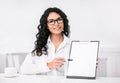 Smiling latin woman showing blank clipboard at office Royalty Free Stock Photo