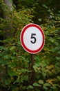 A sign indicating a speed limit of five miles per hour is in the park, in the forest Royalty Free Stock Photo