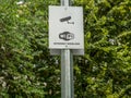 A sign on a metal pole in a park with Wi Fi internet wireless and a security camera