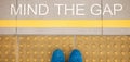 The sign Mind the gap painted on train station's platform edge