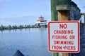 Sign for no crabbing, no fishing and no swimming from the pier. Choptank River Lighthouse in Maryland blurred in background