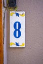 A sign with the number 8 in blue on a pink wall Royalty Free Stock Photo