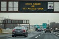 Sign over a multi-lane highway that says Drive Sober or get Pulled Over. There is also an electronic speed limit sign