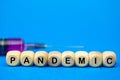 The sign Pandemic on wooden cubes and syringe, blue background. Medical concept, epidemic diseases