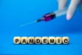 The sign Pandemic on wooden cubes and syringe, blue background. Medical concept, epidemic diseases