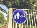 Sign for pedestrians and cyclists on a white fence near a road in the park Royalty Free Stock Photo