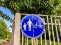 Sign for pedestrians and cyclists on a white fence near a road in the park Royalty Free Stock Photo