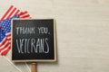 Sign with phrase Thank You, Veterans and American flags on white wooden table, flat lay. Space for text Royalty Free Stock Photo