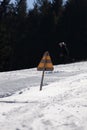 A yellow sign in the middle of a ski slope