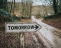 A sign post pointing down a countryside road with the word - Tomorrow Royalty Free Stock Photo
