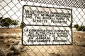 Sign at a prison fence with barbed wire limiting contact with inmates in both english and spanish