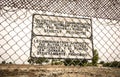 Sign at a prison fence with barbed wire limiting contact with inmates in both english and spanish