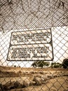 Sign at a prison fence with barbed wire limiting contact with inmates in both english and spanish