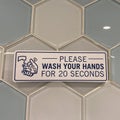 A sign in a public restroom that tells people to please wash your hands for 20 seconds