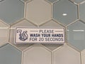 A sign in a public restroom that tells people to please wash your hands for 20 seconds