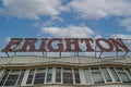 A sign reading Brighton with a blue sky and clouds in the background