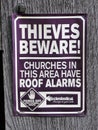 Sign reading Thieves beware, churches in this area have roof alarms. Hands off our church roofs.