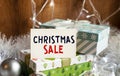 A sign that reads CHRISTMAS SALE stands on the table with gift boxes in the background. Christmas background with decorations from Royalty Free Stock Photo