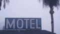 Sign of road motel or hotel, foggy misty weather California, USA. Palm trees.