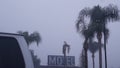 Sign of road motel or hotel, foggy misty weather California, USA. Palm trees.