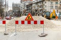 The sign of road works on red white barrier in front of a pile of gravel on a city street. Construction and repair of asphalt Royalty Free Stock Photo