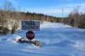 A sign saying trail closed above a stop sign on a snow covered road at a wash-out bridge in the forest Royalty Free Stock Photo