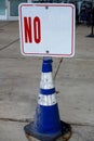 A sign that says no on an old blue and white cone on a sidewalk