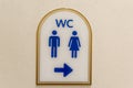A sign showing the direction of toilets with blue silhouettes