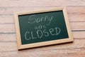 Sign `Sorry, we are closed` on a chalk board with English inscriptions on a wooden background. Royalty Free Stock Photo