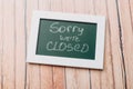 Sign `Sorry, we are closed` on a chalk board with English inscriptions on a wooden background. Closed business Royalty Free Stock Photo