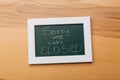 Sign `Sorry, we are closed` on a chalk board with English inscriptions on a wooden background. Closed business Royalty Free Stock Photo