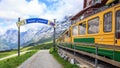 Sign of Starting point to begin walking trail with view of Swiss wengernalpbahn railways train departing Kleine Scheidegg station