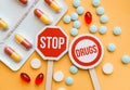 Sign Stop drugs. Colorful pile of medicines and painkillers on yellow background