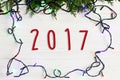 2017 sign text on christmas frame of garland lights on fir branches. stylish border on white rustic wooden background. space for Royalty Free Stock Photo